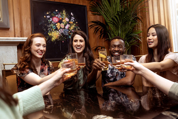 (A group of three women and one man, drinking whisky together) The Modern Face of Whisky if a photo library that represents all whisky drinkers, not just the kind of faces typically seen in the industry
